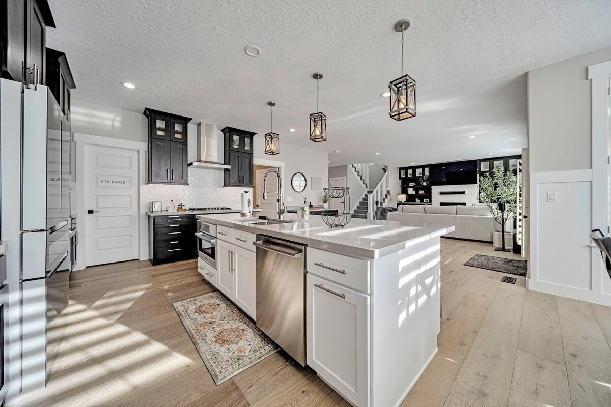Main-floor kitchen with a large island, dark cabinetry, and pendant lighting